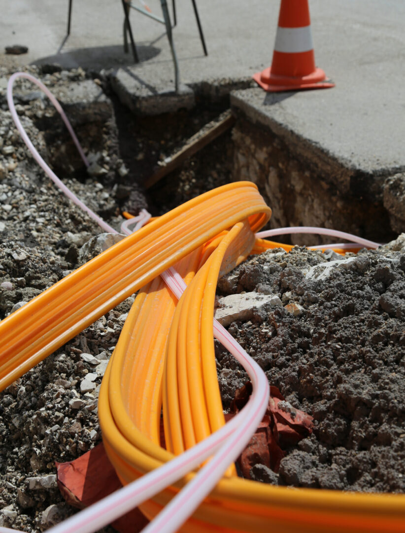 Orange fiber optic cables in trench.