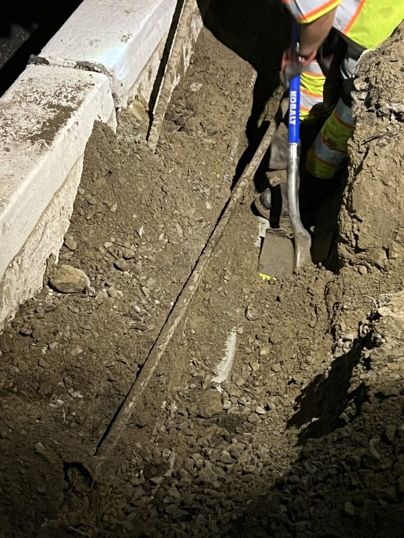 Worker digging up underground pipe.